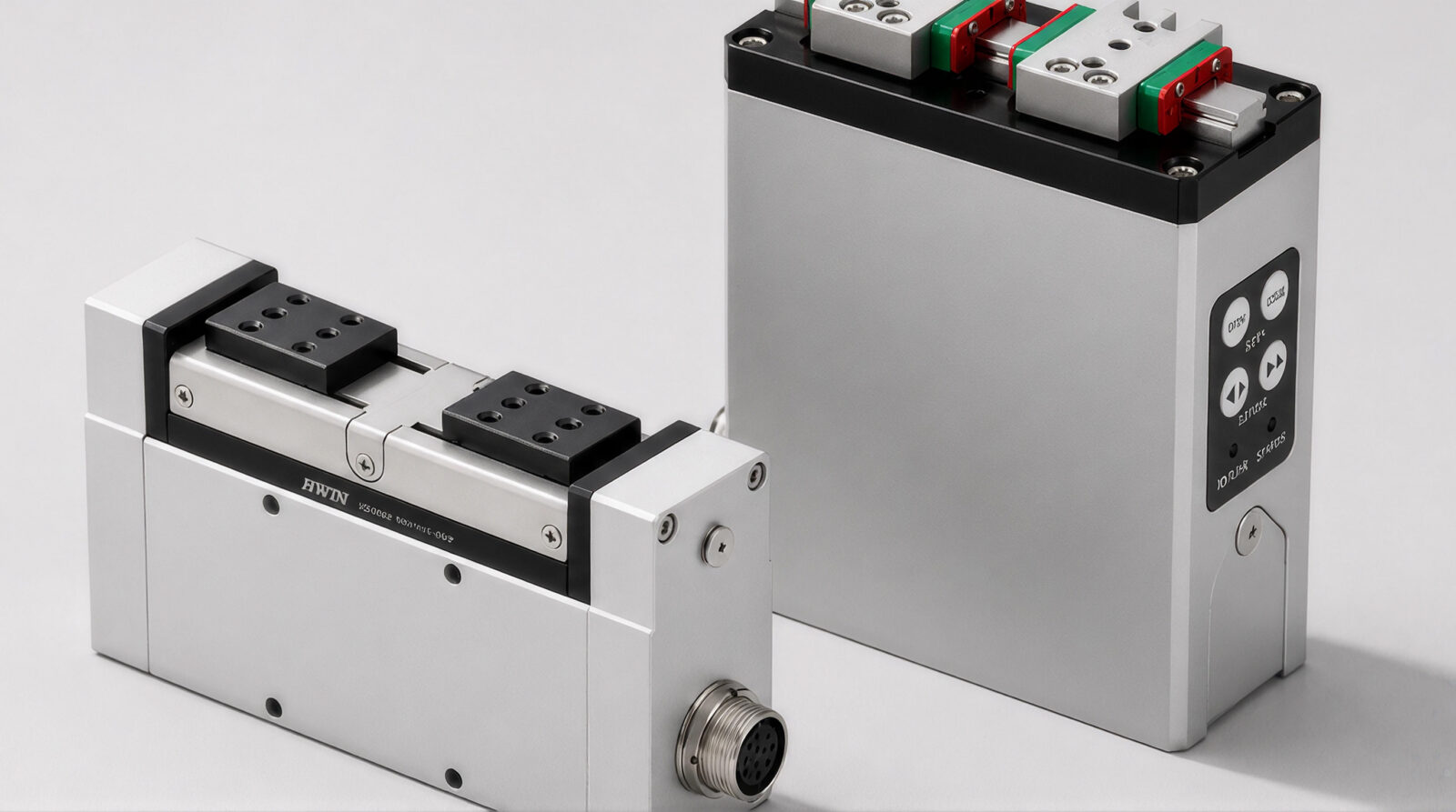 Two industrial linear actuators with metal housings and black accents are displayed; one lies horizontally showing a connector port, while the other stands vertically with visible control buttons and a connector port.
