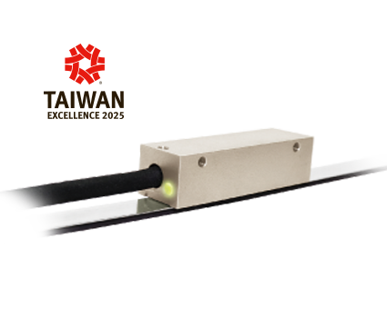A rectangular metallic sensor with a black cable and glowing green indicator, positioned on a reflective surface. The Taiwan Excellence 2025 logo appears in the background.